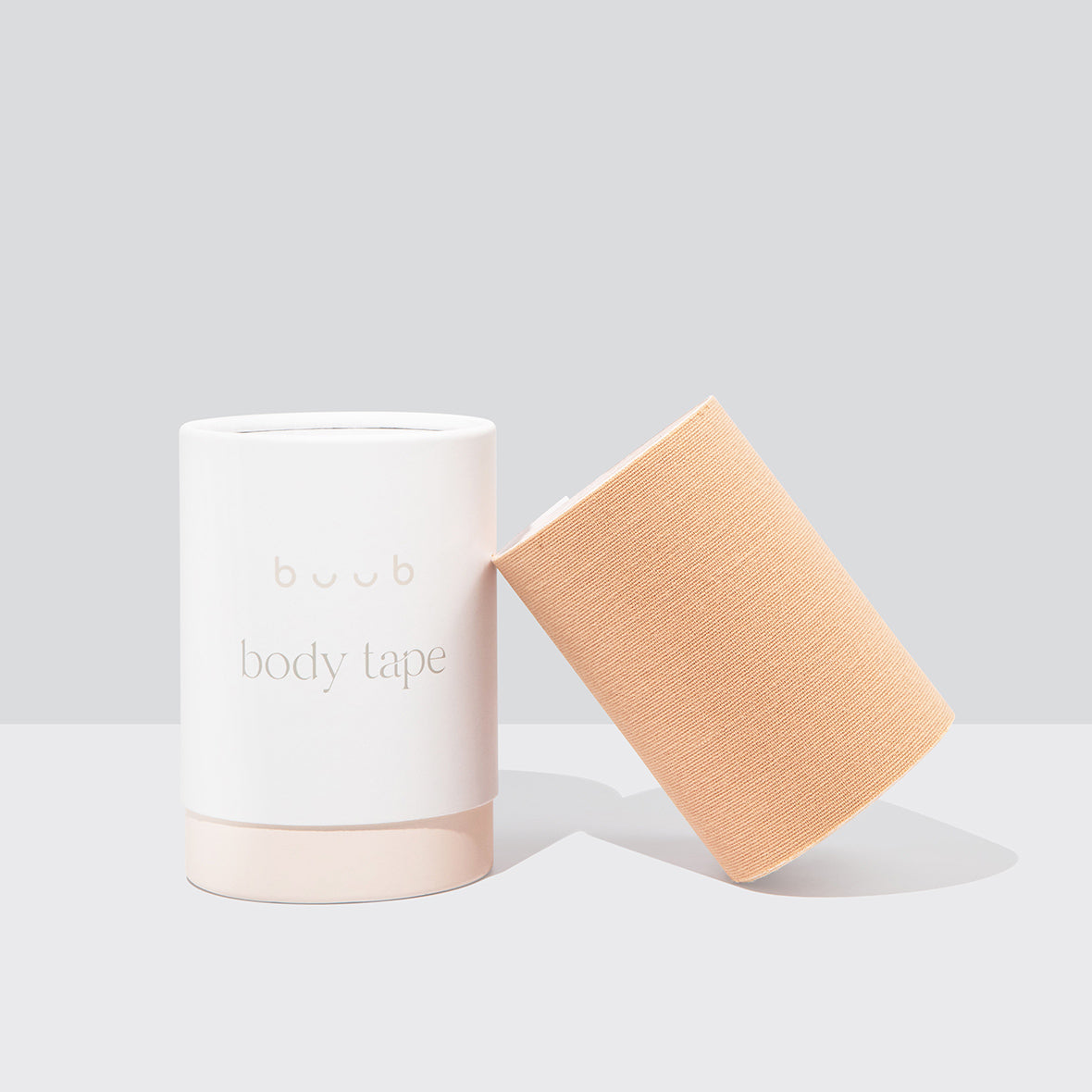 Buub Ultra Body Tape in a nude shade for maximum lift and support. The extra-wide roll of strong-hold boob tape is shown next to its minimalist packaging.