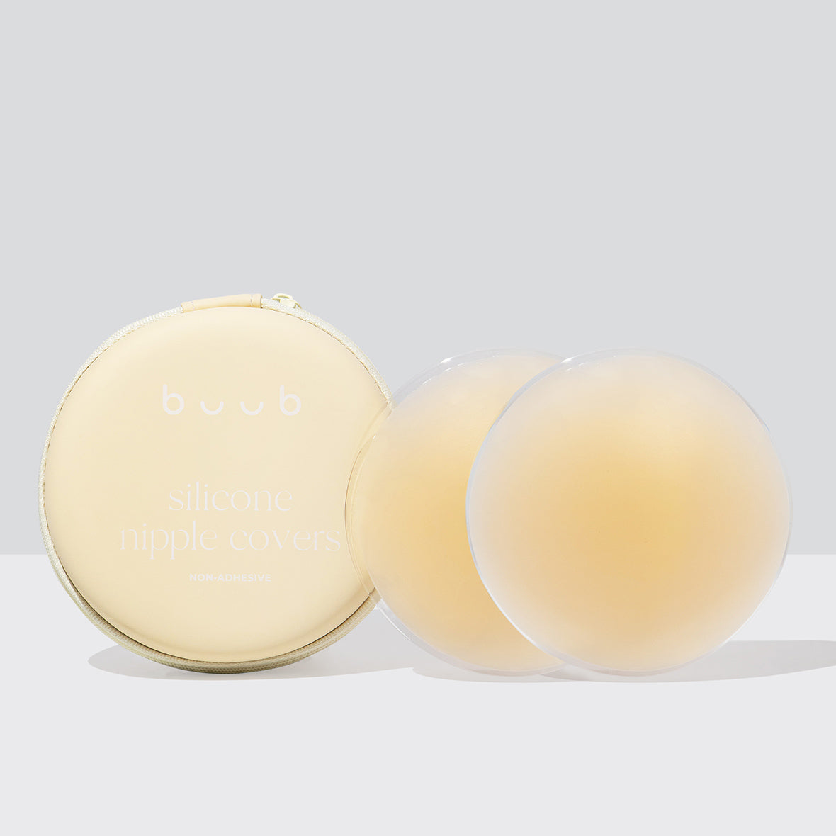Buub's large 10cm reusable adhesive silicone nipple covers in a light nude shade, displayed next to their protective light blue zippered case for storage and travel.