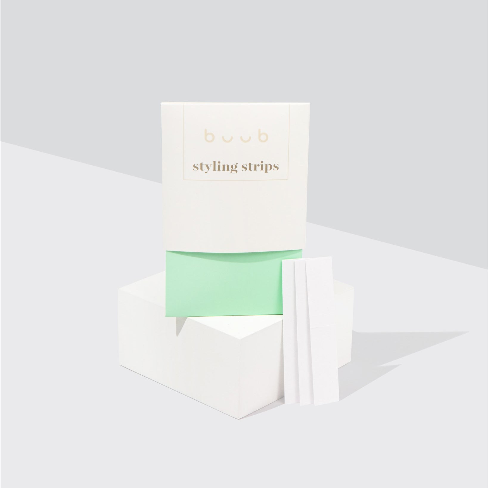 Buub Styling Strips, a double-sided fashion tape for securing clothing. The minimalist white and mint green packaging is displayed on a white block with several individual strips shown.